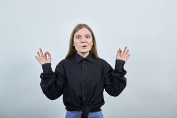 Attractive caucasian blonde young woman in fashion black shirt keeping fingers together,...