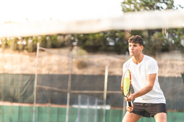 Young Man Playing Tennis Outdoors.