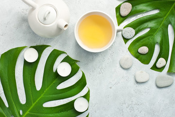 Oriental style  teapot on light   background with green monstera leaves © amberto4ka