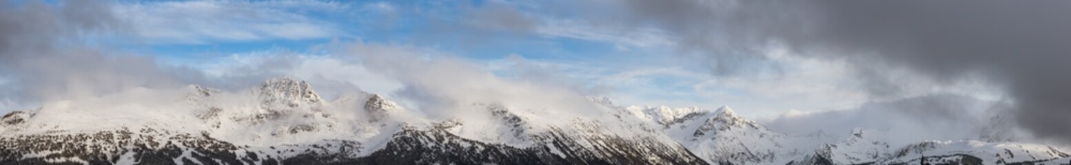 Obraz premium Whistler, British Columbia, Canada. Beautiful View of the Canadian Snow Covered Landscape with Blackcomb Mountain in Background during a cloudy and foggy winter day.