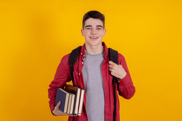 young man or teenage student isolated on color background with backpack and books