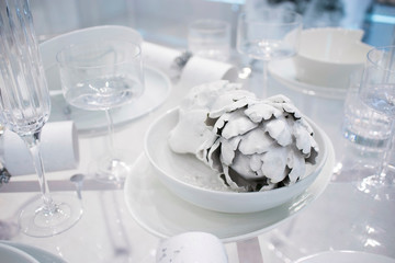 Christmas festive table decoration in white colors. Painted white artichoke in ceramic plate