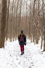 Woman walking on snow covered trail in forest