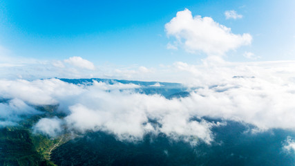 Aerial view of green valley beneath cumulus clouds
