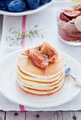 A stack of homemade pancakes with fig jam on a white plate
