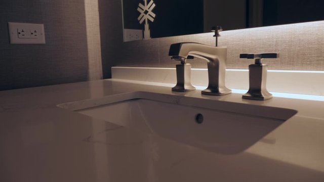 footage of a vanity, brushed nickel faucet, electrical outlet, lotion bottle, and a marble countertop. moving left to right. Slowed to half speed