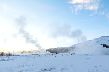 An erupting soaring geyser in the Valley of Geysers. Magnificent Iceland in the winter.