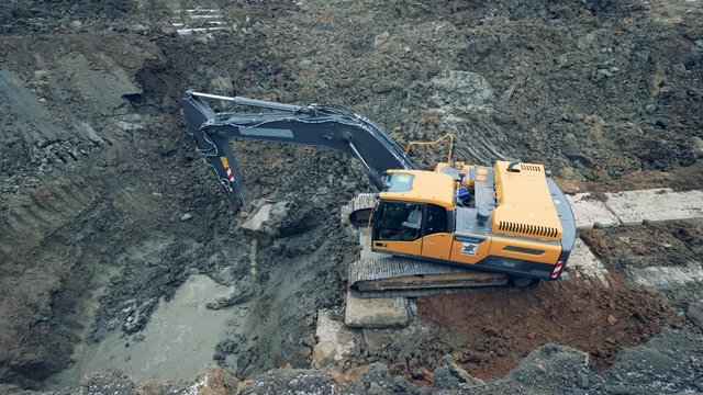 Working tractor scoops sand from a pit.
