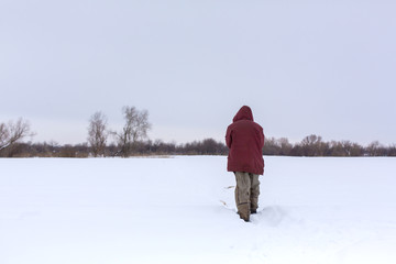 A village man walks in the winter in the field