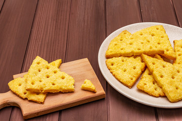 Cheese crackers, salty snack concept. Cookies, plate, cutting board. Wooden planks background