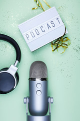 Top view photo of podcast concept - lightbox with letters podcast on it, headphones and...