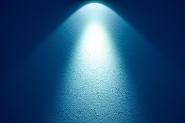 Eine helle Lampe erzeugt einen Lichtstrahl auf einer Wand.