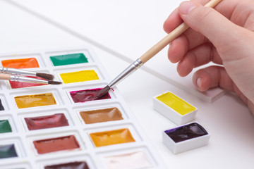 Watercolor art paint. Brush in hand. A palette of multi-colored paints for drawing with water. on white background