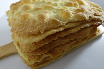 Folded baked sheets of puff pastry to make the pie on a white wooden surface. Horizontal orientation. Close-up.