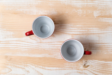 Two empty cups on a light brown table. Directly above