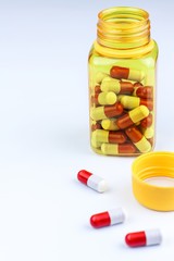 Red-white tablets on white background. Medicines in yellow jar. Pharmaceutical industry concept. Treatment of disease. Vitamin supplements.