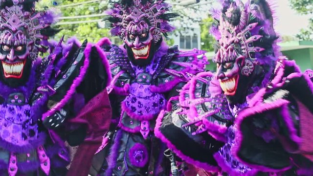 people in violet demon costumes dance at traditional dominican carnival annual event