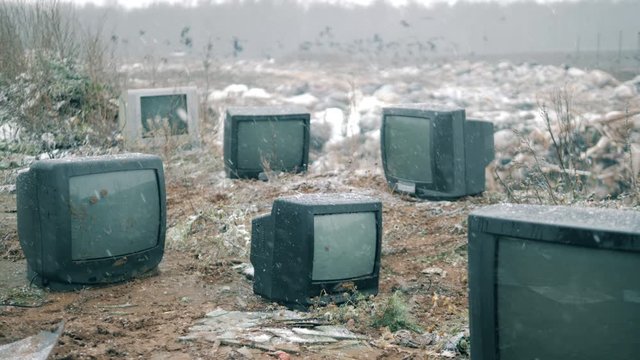 Snowfall at the grabage dump with thrown-out TVs