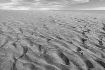 Black and white photo of the sand in the Dunes of Maspalomas, a small desert on Gran Canaria, Spain. Sand and sky.