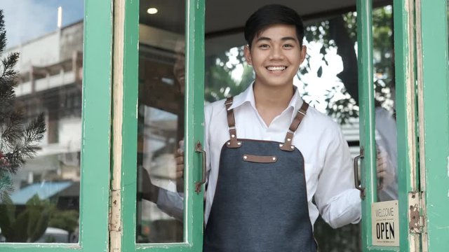 Young entrepreneur man open the door in the morning at his coffee cafe shop.