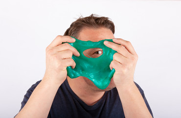 Funny dad holding a green slime in front of his stubbled face and looking through its hole