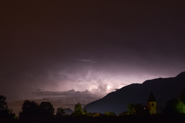 Lightning in a thunderstorm at night over Italy, viewed from a scenic town in Slovenia