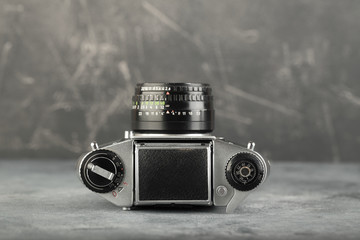 The old 35 mm SLR camera with lens on a grey cement background.