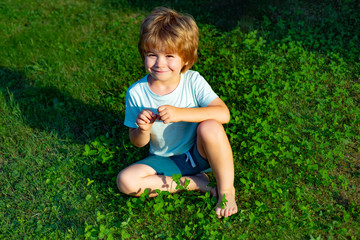 Kid on the grass. Happy boy on the green lawn. Lawn near the family house. Childrens smile on a sunny day.
