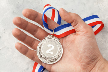Silver medal. The second place award with a ribbon a man holds in his hand