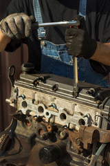 Mechanik samochodowy w stroju roboczym odkręca śruby w silniku. Odkręcanie pokrywy zaworów silnika samochodowego. - obrazy, fototapety, plakaty