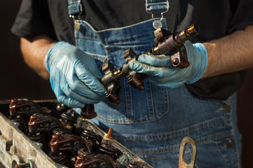 Dłonie mechanika samochodowego w rękawicach jednorazowych trzymają element silnika. Remont silnika, demontaż silnika samochodowego. - obrazy, fototapety, plakaty