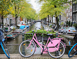 Fototapeta na wymiar Pink bike on a bridge with the canal in Amsterdam. 