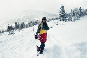 Female snowboarder with snowboard in the mountains on a snowy slope.