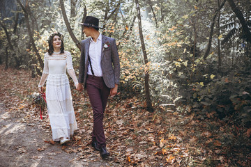 Bride and Stylish Groom. Happy wedding couple at a wedding ceremony outdoors in the park during sunset. Atmospheric glow of the sun and beautiful lovers - Perfect Wedding background