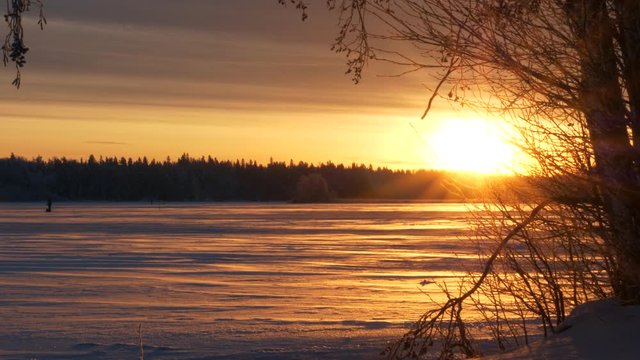 Sunlight lighting up frozen lake, snow landscape during winter solstice