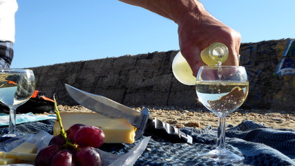Picknick am Strand mit prickelndem Schaumwein, Käse und roten Weintrauben