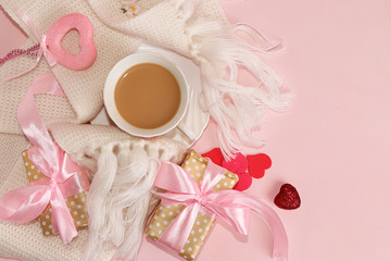 Greeting card for Valentine's day or Women's Day with a cup of coffee. Red hearts and gift box on a pink background, top view. Congratulations on the holiday, concept of modern woman, Hygge style.