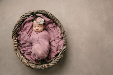 full length sweet newborn baby girl swaddled and bundled up in a blanket wrap laying in a wooden...