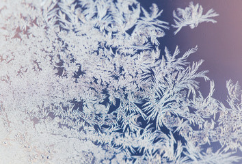 Magical frost ornaments on the window. Closeup of frozen ice on the glass. Macro shot with shallow depth of field.