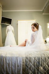 Fototapeta na wymiar The bride in a white coat on the bed in a wedding morning