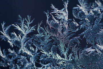 Magical frost ornaments on the window. Closeup of frozen ice on the glass. Macro shot with shallow...