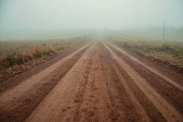 Fototapeta na wymiar Landscape with dirt road in a foggy day