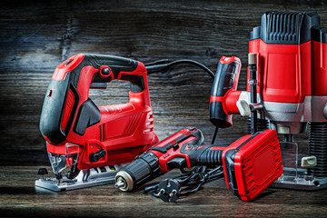 electric hand tools red corded jigsaw cordless drill and small plunge router milling machine portable mini wood router on vintage wooden background