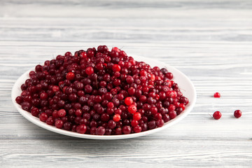 Ripe cranberry berries on a light wooden table.