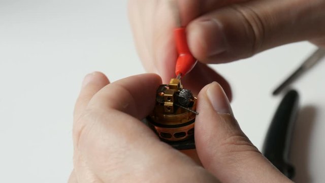 A man inserts new cotton wool in an electronic brown cigarette
