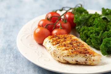 Grilled Chicken Breast with roasted Cherry Tomatoes. Bright wooden background. 