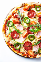 Pizza with ham, salami, jalapeno pepper, cherry tomatoes, cheese and rocket. Top view.	