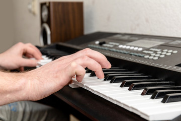 Fototapeta premium hands of a pianist man playing a synthesizer in a bright home studio