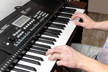 Fototapeta na wymiar hands of a pianist man playing a synthesizer in a bright home studio