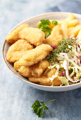 Chicken nuggets with raw salad and french fries on bright wooden background. 
